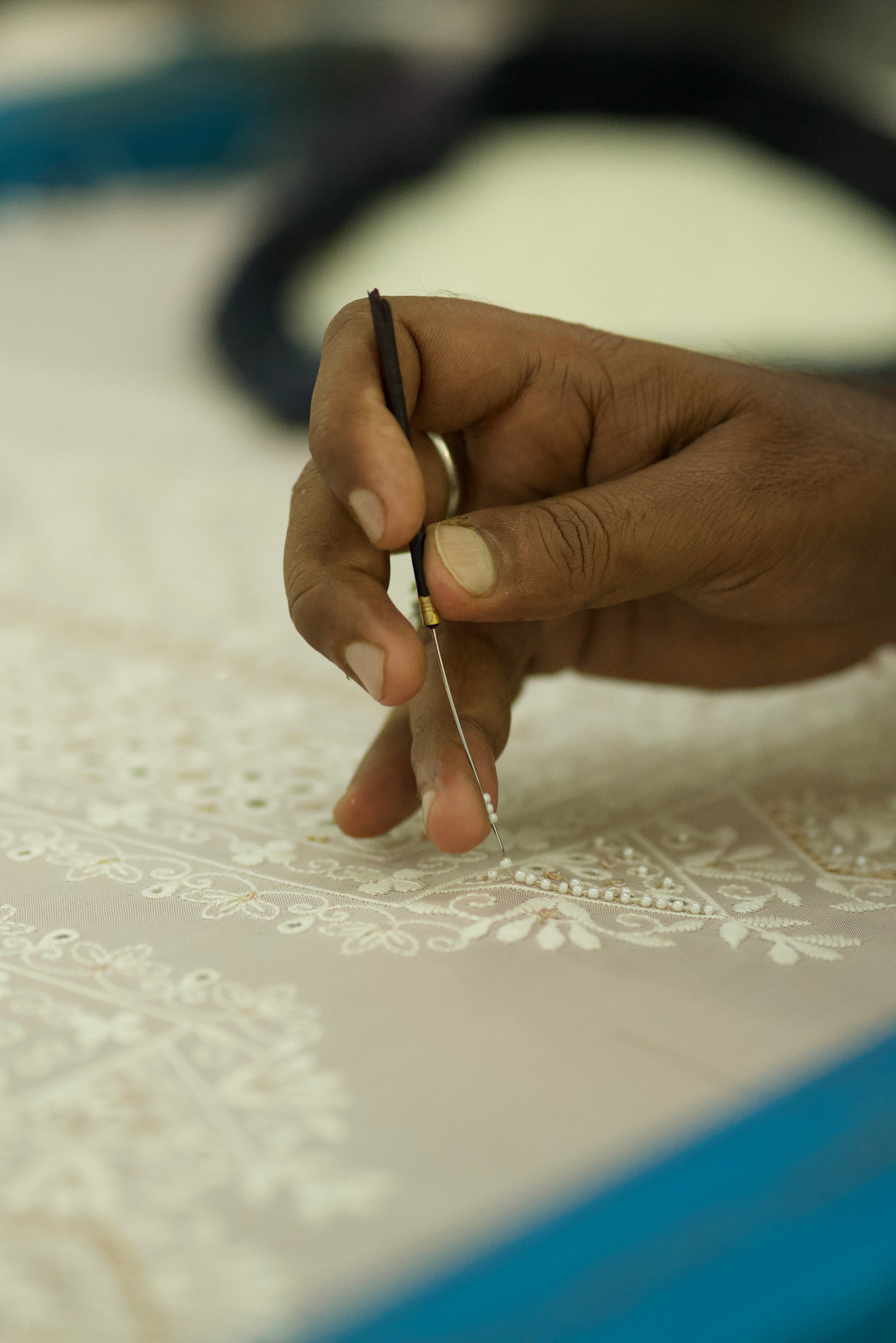 Hand holding a needle and thread against a textured fabric background